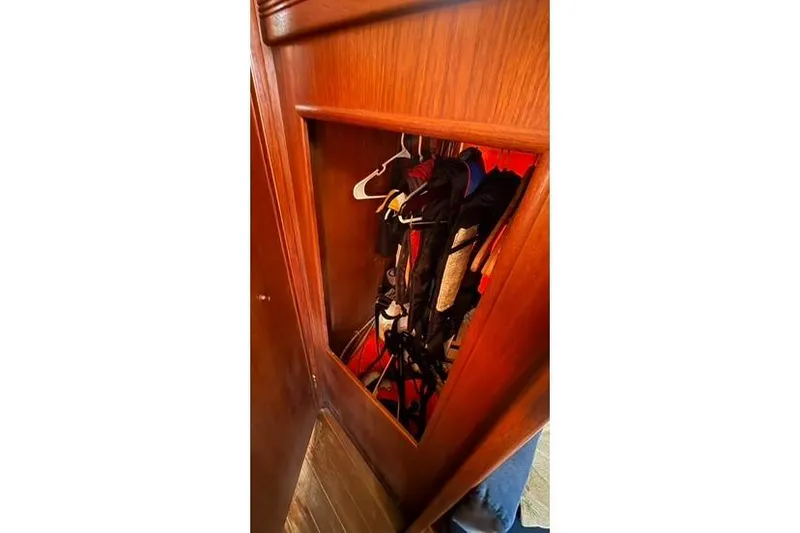 Slide: The Image of Wooden closet interior on a 1985 Sabre 32 sailboat, filled with hanging clothes. - 16