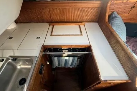 Slide: The Image of 1985 Sabre 32 yacht galley with wood accents, sink, and stove. - 17