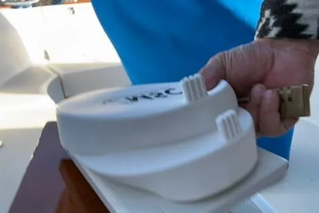 Slide: The Image of Hand holding a marine device on a 1985 Sabre 32 boat deck. - 21
