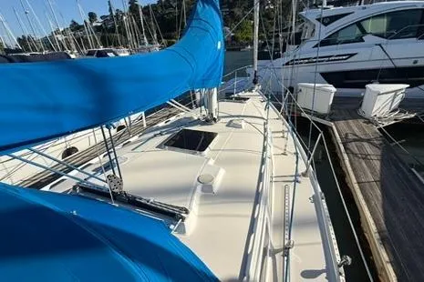 Slide: The Image of 1985 Sabre 32 sailboat with blue sails docked at a marina. - 23