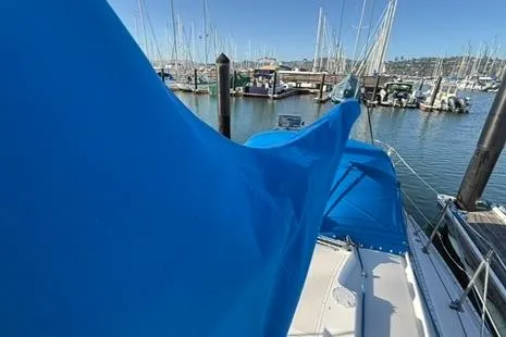 Slide: The Image of 1985 Sabre 32 sailboat with blue cover docked in a marina. - 25