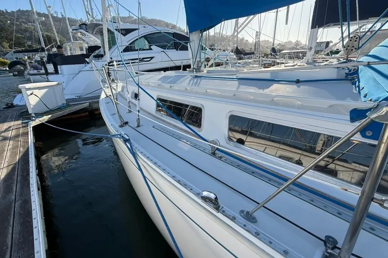 Slide: The Image of 1985 Sabre 32 sailboat docked at marina, featuring sleek white hull and blue accents. - 32