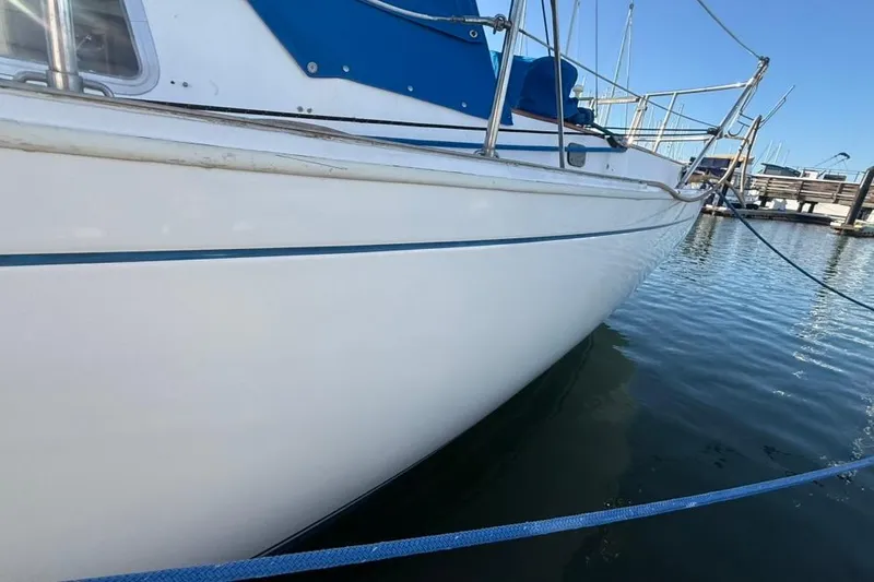 Slide: The Image of 1985 Sabre 32 sailboat docked in marina, featuring sleek white hull and blue accents. - 34