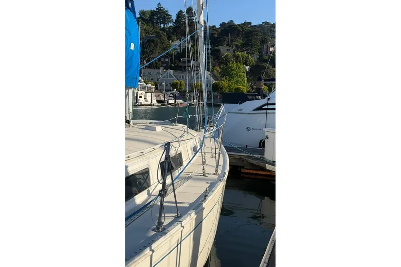 Slide: The Image of 1985 Sabre 32 sailboat docked in a scenic marina with hillside homes. - 42