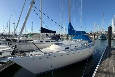 Slide: The Image of 1985 Sabre 32 sailboat docked at marina, surrounded by other boats under clear blue sky. - 5