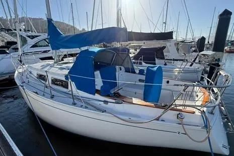 Slide: The Image of 1985 Sabre 32 sailboat docked in marina, featuring blue covers and sleek design. - 6