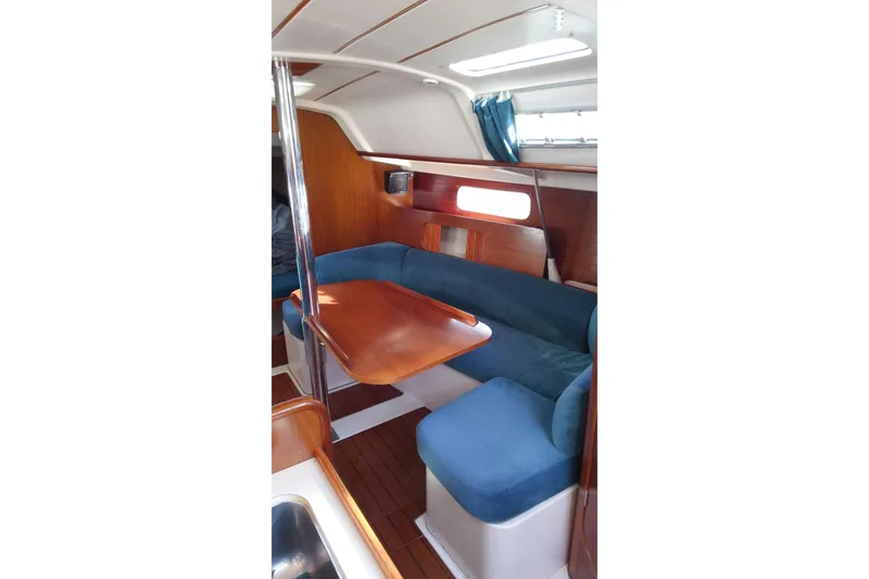 Slide: The Image of Interior of 1996 Beneteau Oceanis 321 sailboat with blue seating and wooden table. - 18