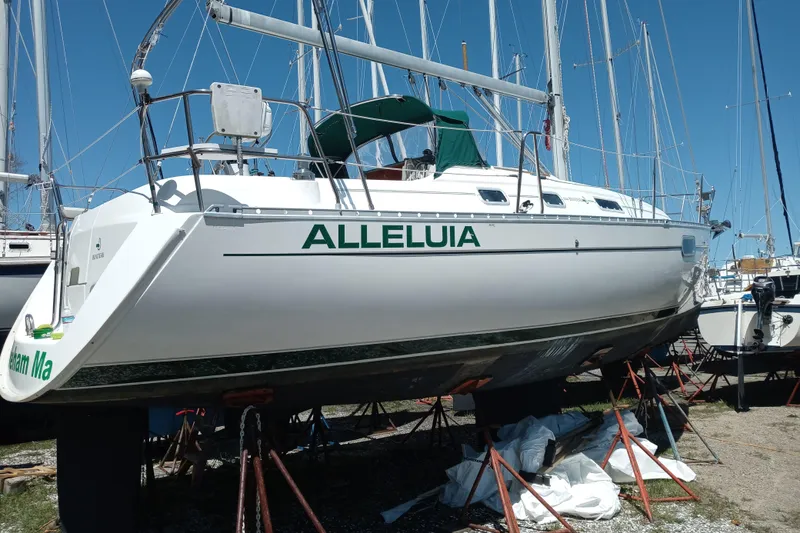Slide: The Image of 1995 Beneteau Oceanis 321 sailboat on stands, named "Alleluia," in a marina. - 2