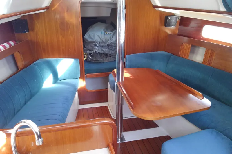Slide: The Image of Interior of 1996 Beneteau Oceanis 321 sailboat with blue seating and wooden table. - 20