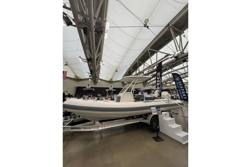 Slide: The Image of 2026 Brig Eagle 6.7 boat displayed indoors on a trailer at a boat show. - 2