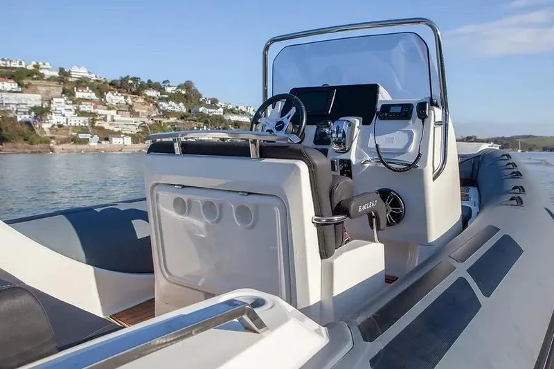 Slide: The Image of Manufacturer Provided Image: 2026 Brig Eagle 6.7 boat interior with steering console, on calm water near coastal homes. - 7