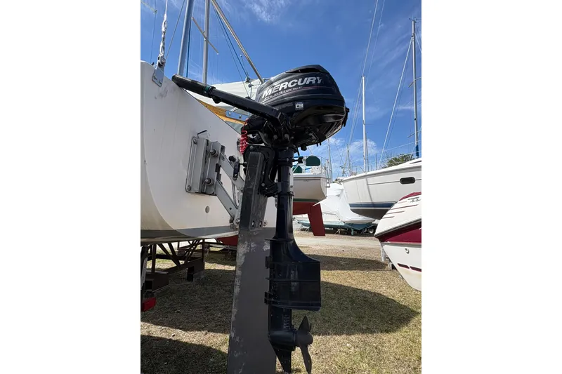 Slide: The Image of 1982 J Boats J/24 with Mercury outboard motor, docked on land under clear blue sky. - 3