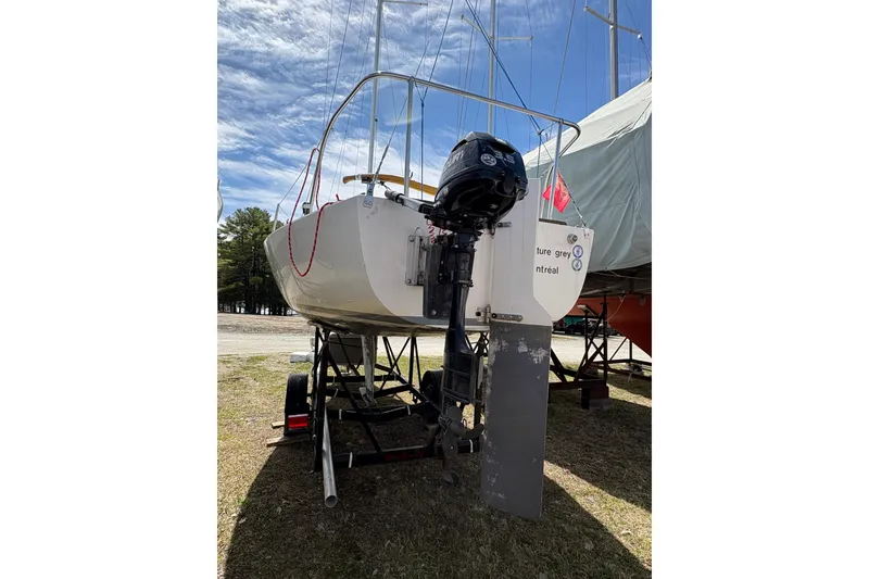 Slide: The Image of 1982 J Boats J/24 sailboat on trailer with outboard motor, under clear sky. - 4
