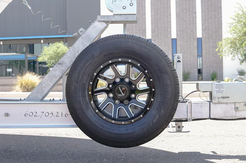 Slide: The Image of Trailer wheel of 2024 NauticStar 292 Legacy boat, featuring black alloy rim and tire. - 34