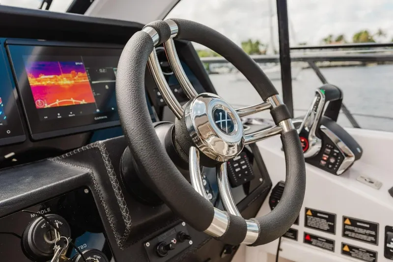 Slide: The Image of Steering wheel and controls of a 2027 Hanover 415 boat, featuring advanced navigation displays. - 2