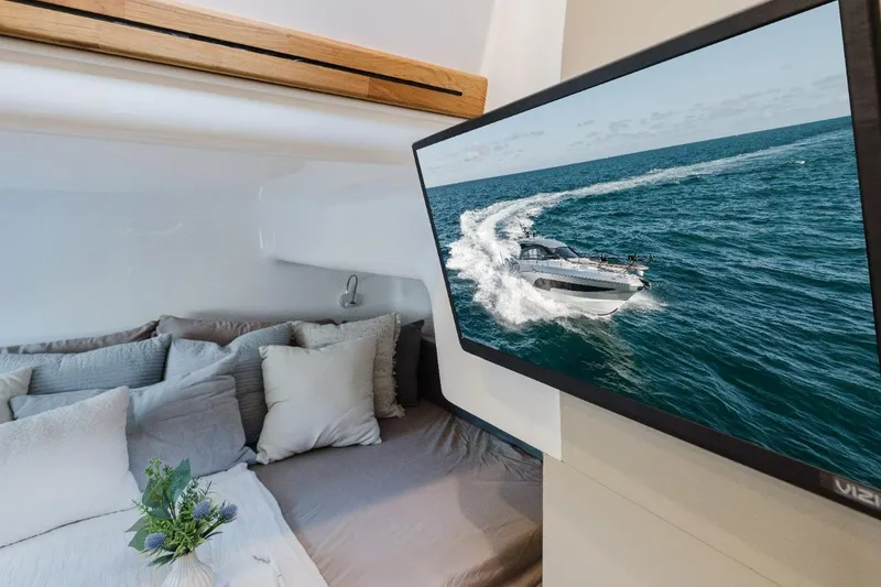 Slide: The Image of Luxurious Hanover 415 yacht interior with cozy bed and ocean view on TV, 2027 model. - 8