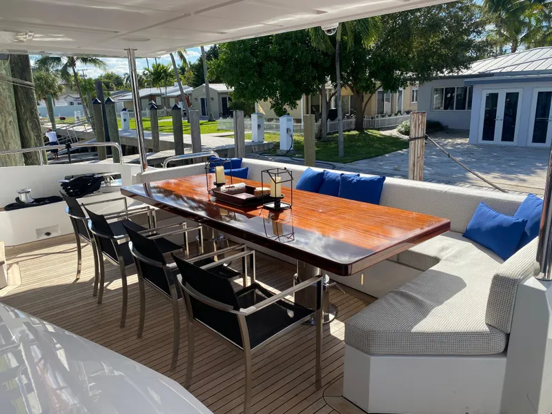 Slide: The Image of Outdoor dining area on 2014 Azimut 100 Grande yacht with wooden table and cushioned seating. - 10