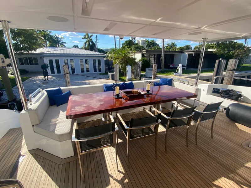 Slide: The Image of Outdoor dining area on 2014 Azimut 100 Grande yacht with wooden table and cushioned seating. - 38