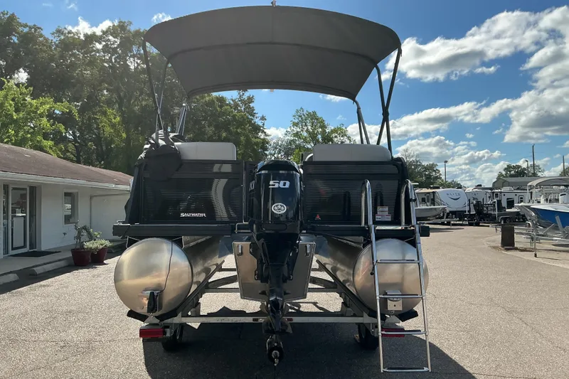 Slide: The Image of 2025 Qwest E-Class RLS 16 pontoon boat with canopy and outboard motor in a sunny marina. - 3