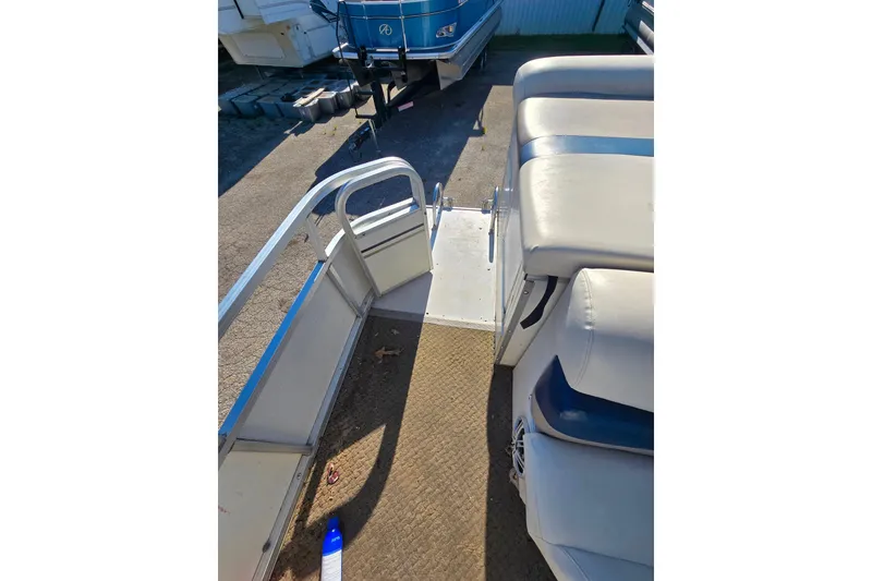 Slide: The Image of 2005 Lowe Jamaica 250SD boat interior with seating and railing, docked outdoors. - 11