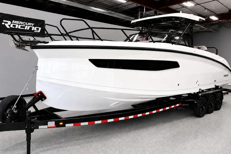 The Image of 2026 Navan S30 boat on trailer in showroom, featuring sleek white design and Mercury Racing branding. - 0