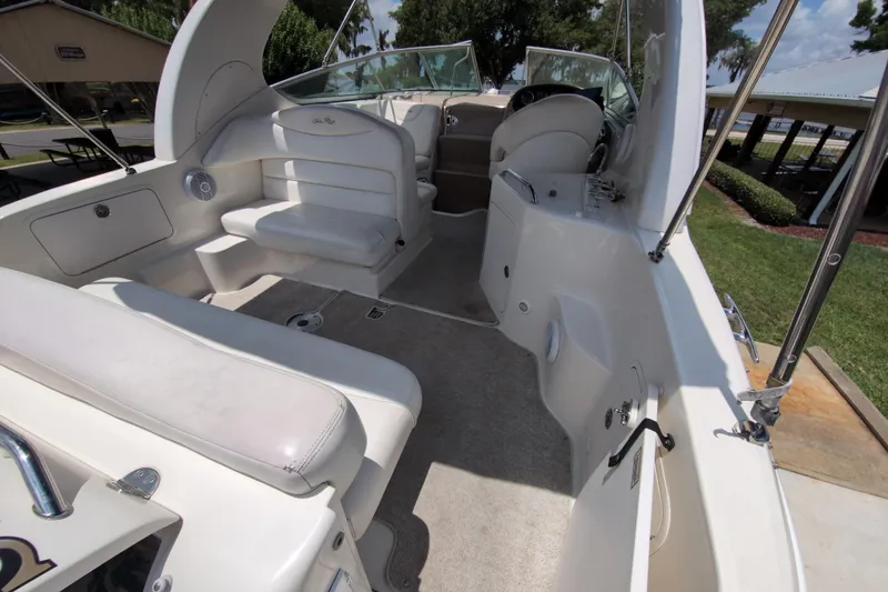 Slide: The Image of 2005 Sea Ray Sundancer 280 interior with white seating and helm, docked outdoors. - 13