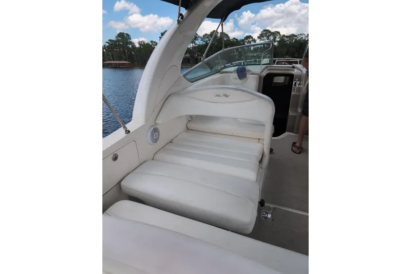 Slide: The Image of 2005 Sea Ray Sundancer 280 interior with white seating, docked by a serene lake. - 14