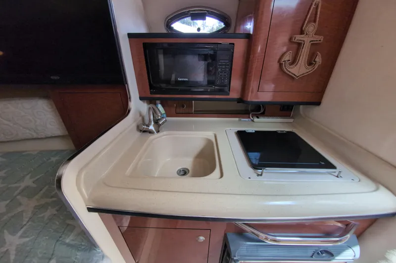Slide: The Image of 2005 Sea Ray Sundancer 280 galley with sink, microwave, and stove. - 43