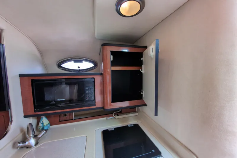 Slide: The Image of 2005 Sea Ray Sundancer 280 interior kitchen with microwave, open cabinet, and sink. - 44