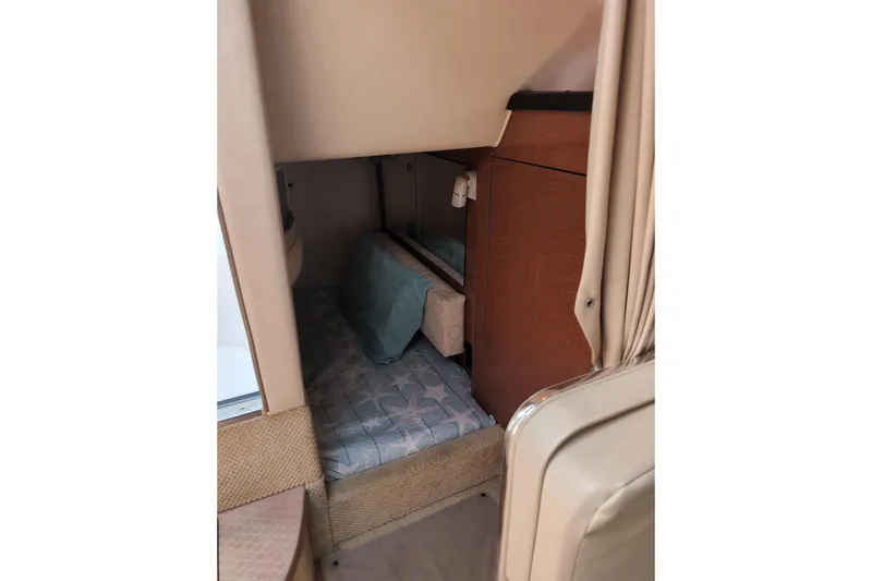 Slide: The Image of 2005 Sea Ray Sundancer 280 cabin interior with cozy sleeping area and wooden cabinetry. - 57