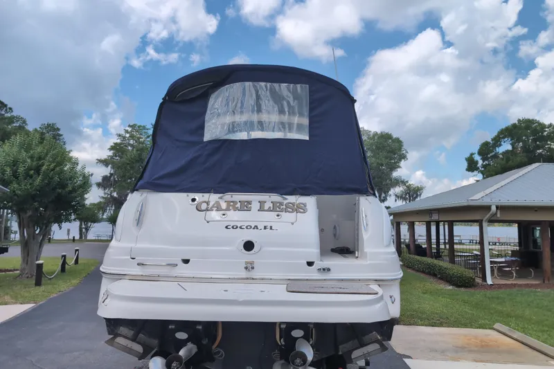 Slide: The Image of 2005 Sea Ray Sundancer 280 boat with blue cover, parked near a lakeside pavilion. - 7