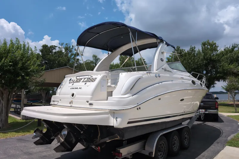 Slide: The Image of 2005 Sea Ray Sundancer 280 boat on trailer, parked outdoors under a blue sky. - 84
