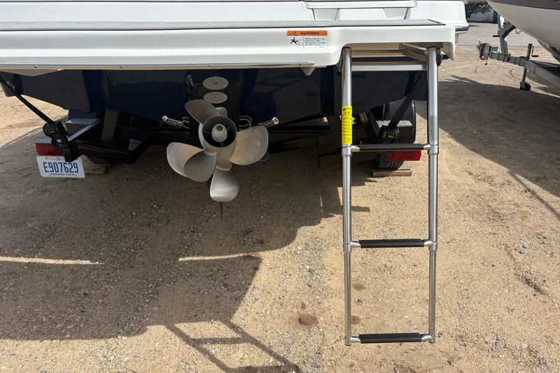 Slide: The Image of 2023 Four Winns HD3 boat stern with ladder and propeller on sandy ground. - 3