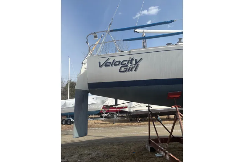 The Image of 1976 J Boats J/29 sailboat named "Velocity Girl" on a stand outdoors. - 1