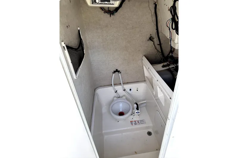 Slide: The Image of 2004 Robalo R230 Center Console boat interior with compact marine toilet setup. - 12
