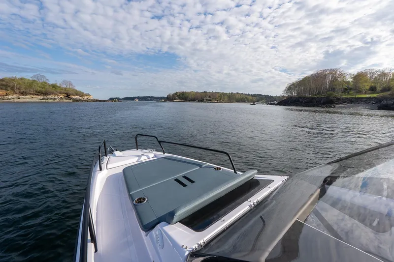 Slide: The Image of 2025 Axopar Cross Top boat cruising on a scenic lake with lush shoreline. - 10