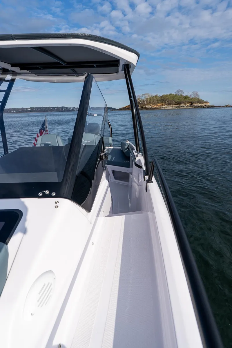 Slide: The Image of 2025 Axopar Cross Top boat cruising on calm waters under a partly cloudy sky. - 13
