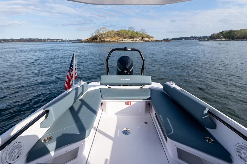 Slide: The Image of 2025 Axopar Cross Top boat with seating, American flag, and scenic water view. - 26
