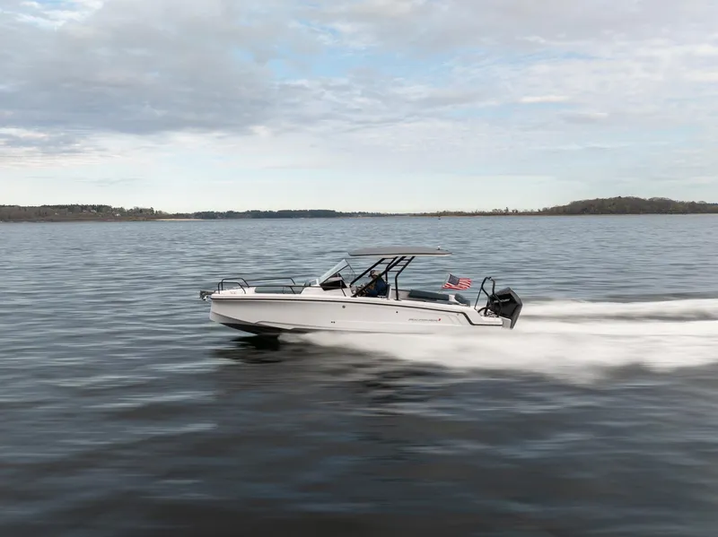 Slide: The Image of 2025 Axopar Cross Top boat cruising on a calm lake under a cloudy sky. - 5