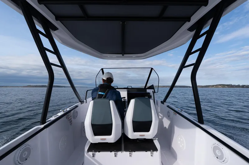 Slide: The Image of 2025 Axopar Cross Top boat on water, rear view with two seats and canopy. - 6