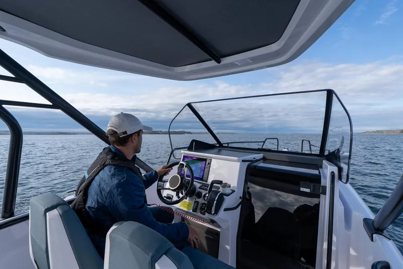 Slide: The Image of Person steering 2025 Axopar Cross Top boat on open water. - 7
