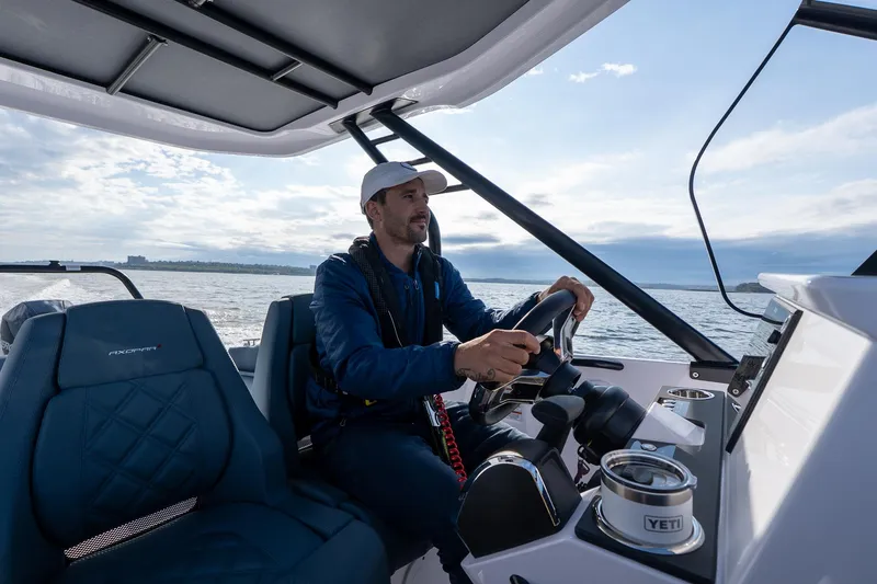 Slide: The Image of Man steering 2025 Axopar Cross Top boat on open water. - 8