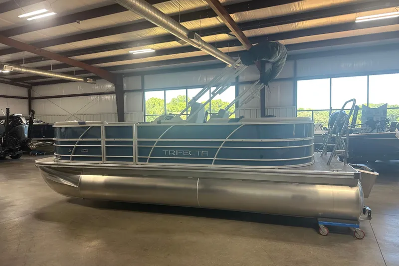 Slide: The Image of 2025 Trifecta 20RFLE2.75 pontoon boat in a spacious indoor showroom. - 4