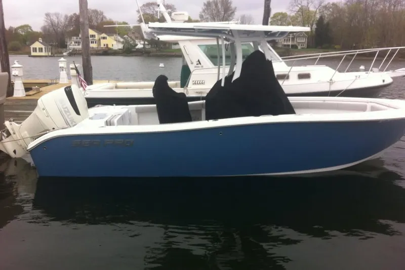 Slide: The Image of 2019 Sea Pro 239 Center Console boat docked, featuring a blue hull and white motor. - 3