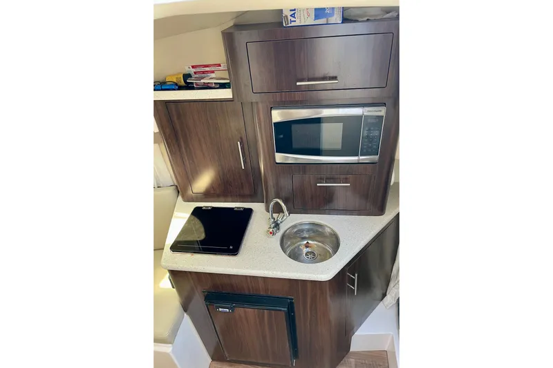 Slide: The Image of Compact kitchen area in a 2016 Regal 28 Express boat with microwave and sink. - 15