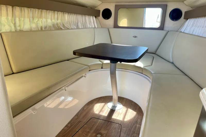 Slide: The Image of Interior of 2016 Regal 28 Express boat with beige seating and wooden table. - 16