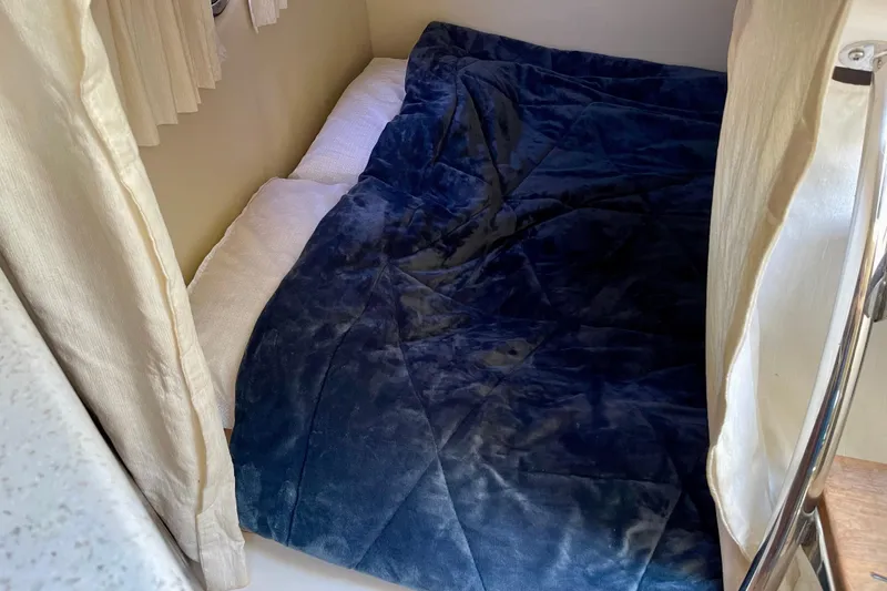 Slide: The Image of Cozy sleeping area in a 2016 Regal 28 Express boat with blue bedding. - 18