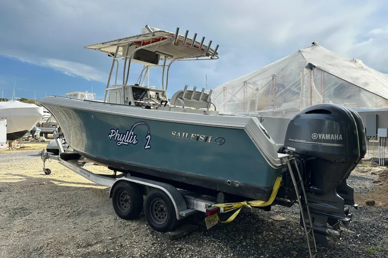 Slide: The Image of 2011 Sailfish 2660 CC boat on trailer with Yamaha engine, parked outdoors. - 2