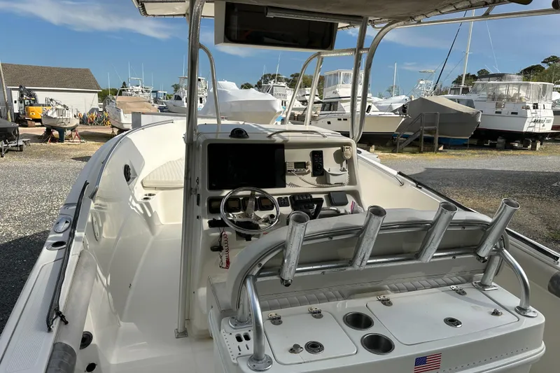Slide: The Image of 2011 Sailfish 2660 CC boat interior with steering console and rod holders in a marina. - 3