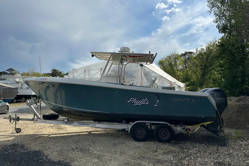Slide: The Image of 2011 Sailfish 2660 CC boat on trailer, parked outdoors under cloudy sky. - 8